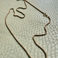 18k Gold chain necklace on a textured light green surface