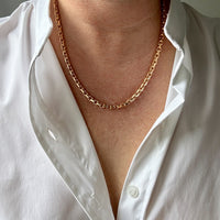 Person wearing a gold chain necklace with a white shirt. Penelope Penelope vintage gold jewelry