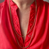 Red shirt with a gold chain necklace on a neutral background