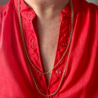 Red shirt with a gold chain necklace on a neutral background