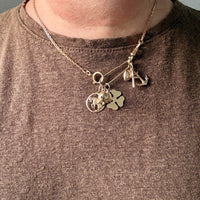 Gold necklace with charms worn by a person against a neutral background