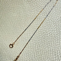 18k Gold and platinum watch chain with clip on a textured beige background