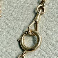 Close-up of a gold chain with a clasp on a textured light gray background
