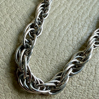 Silver chain necklace on a textured beige surface
