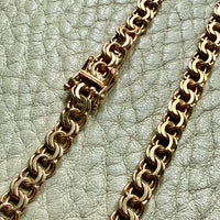 Gold chain necklace on a textured light green surface