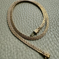 Gold chain necklace on a textured gray surface