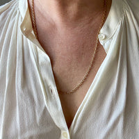 Person wearing a white shirt with a gold necklace
