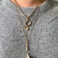 Gold necklaces with pendants on a gray sweater