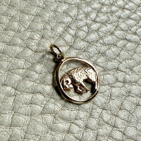 14k gold pendant with an aries ram design on a textured gray surface