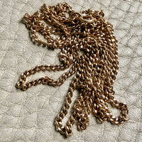 Gold chain necklace on a textured beige surface