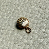 vintage 14k Gold shell charm with a pearl on a textured beige background