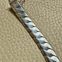 Silver bracelet on a beige leather surface