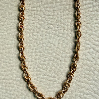 Gold chain necklace on a light gray textured background