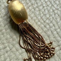 vintage 18k Gold tassel pendant on a textured light gray background penelopepenelope.com