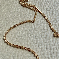 Gold chain necklace on a textured light gray background