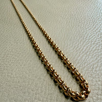 Gold chain necklace on a light gray textured surface