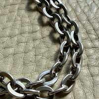 Close-up of a silver chain on a textured beige surface