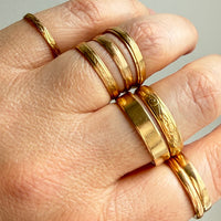 vintage and antique 18k Gold rings on a hand against a neutral background