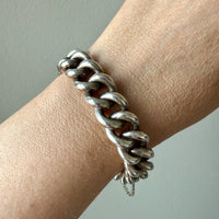 Silver chain bracelet on a wrist against a neutral background
