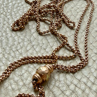 antique 18k gold chain necklace with a decorative clasp on a textured surface