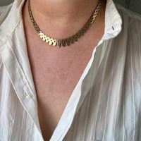 Person wearing a gold necklace with a white shirt