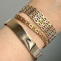 Close-up of a wrist wearing multiple gold bracelets on a gray background