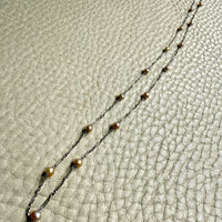 french antique platinum Necklace with pearl beads on a textured beige surface