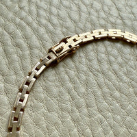 clasp detail 14k Gold vintage chain necklace on a textured gray background
