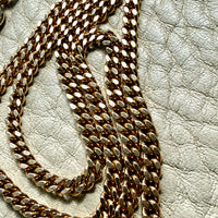 Close-up of a gold chain on a textured beige surface