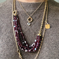 gold Necklaces with maroon beads and gold chain on a brown sweater
