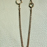 Gold chain necklace on a textured light green background