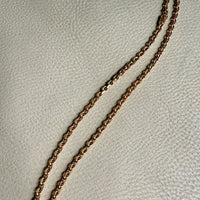 Gold chain necklace on a light gray background