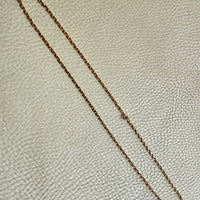 Gold chain on a textured beige surface