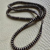 Silver beaded necklace on a textured surface