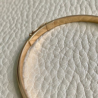 A solid gold hinged bangle made in 1978 in Sävsjö, Sweden. Solid bangles like this are rare finds! What I love about them is that they cannot dent - this style is a solid bar of gold! This amazing vintage Scandinavian 18k gold bangle is oval shaped with a femme half-round cross section. Interior of the oval measures 2 inches (50mm) x 2.4 inches (60mm) and opens with a well working and beautiful hinge. She weighs an excellent 18.2g