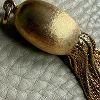 Gold pendant with chain on a textured surface