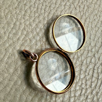 glass locket with gold frames on a textured beige surface