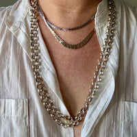 Close-up of a person wearing multiple necklaces with a white shirt.