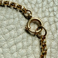 18k Gold antique rolo link necklace clasp detail on a textured light gray surface