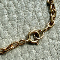 Gold chain bracelet on a textured light gray surface
