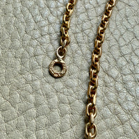 Gold chain necklace with hallmarks on a textured gray surface