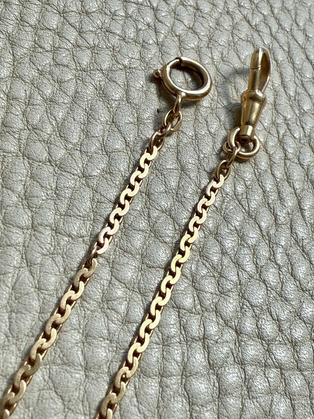 Gold chain necklace with clasp on a textured gray background