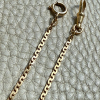 Gold chain necklace with clasp on a textured gray background