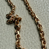 Gold chain necklace on a textured light gray background