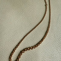 18k Gold vintage graduated rolo chain necklace on a textured beige surface penelopepenelope.com