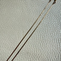 Gold 18k watch chain necklace on a textured light gray surface