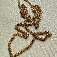 18k Gold antique rolo link necklace on a textured light gray surface