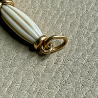 18k gold quizzing glass magnifying glass pendant on a textured light gray background