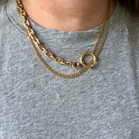 Gold chain necklaces on a person wearing a gray shirt