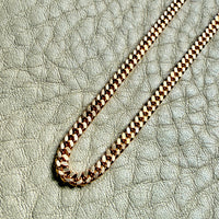 18k Gold curb chain necklace on a textured light surface